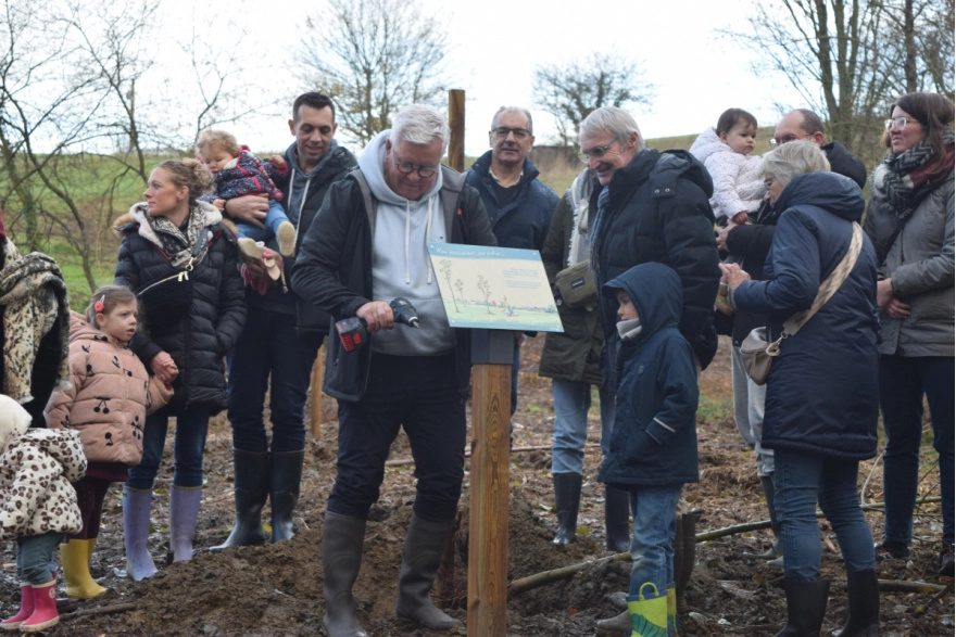 Familles et élus posent ensemble le panneau d'information sur le site de plantation