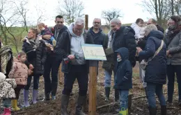 Familles et élus posent ensemble le panneau d'information sur le site de plantation